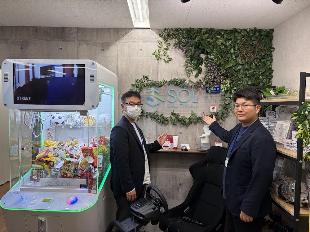 UFOキャッチャーがあるエントランスで出迎えてくれたエスオーエル情報システム部の河出様と下嶋様の写真